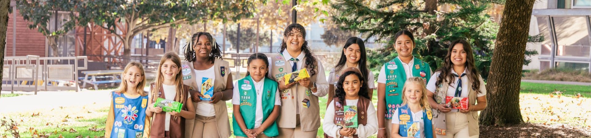  girl scouts selling cookies with one girl in front of booth holding sign that says "girl scout cookie proceeds stay local" 