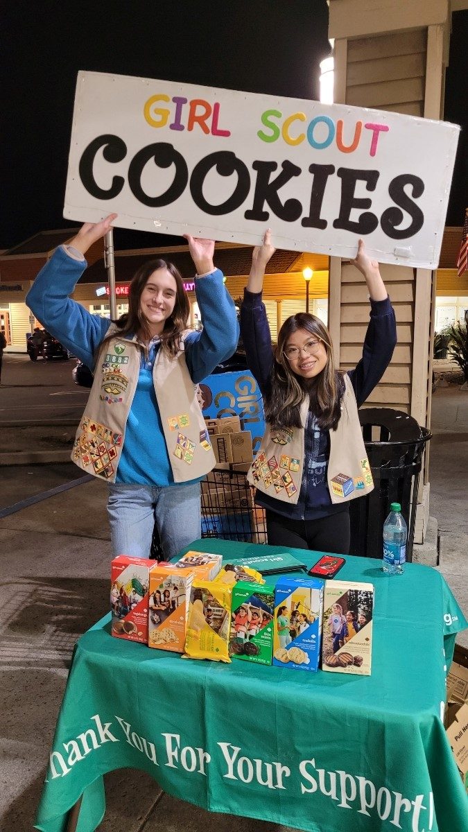 girl scout selling cookies with parent