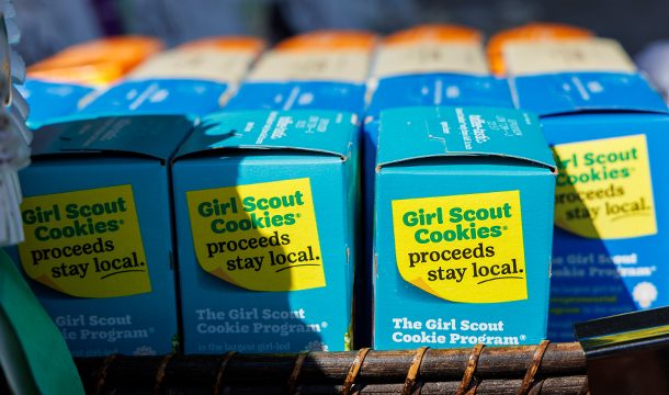 girl scout putting boxes of trefoils into cookie transport bag