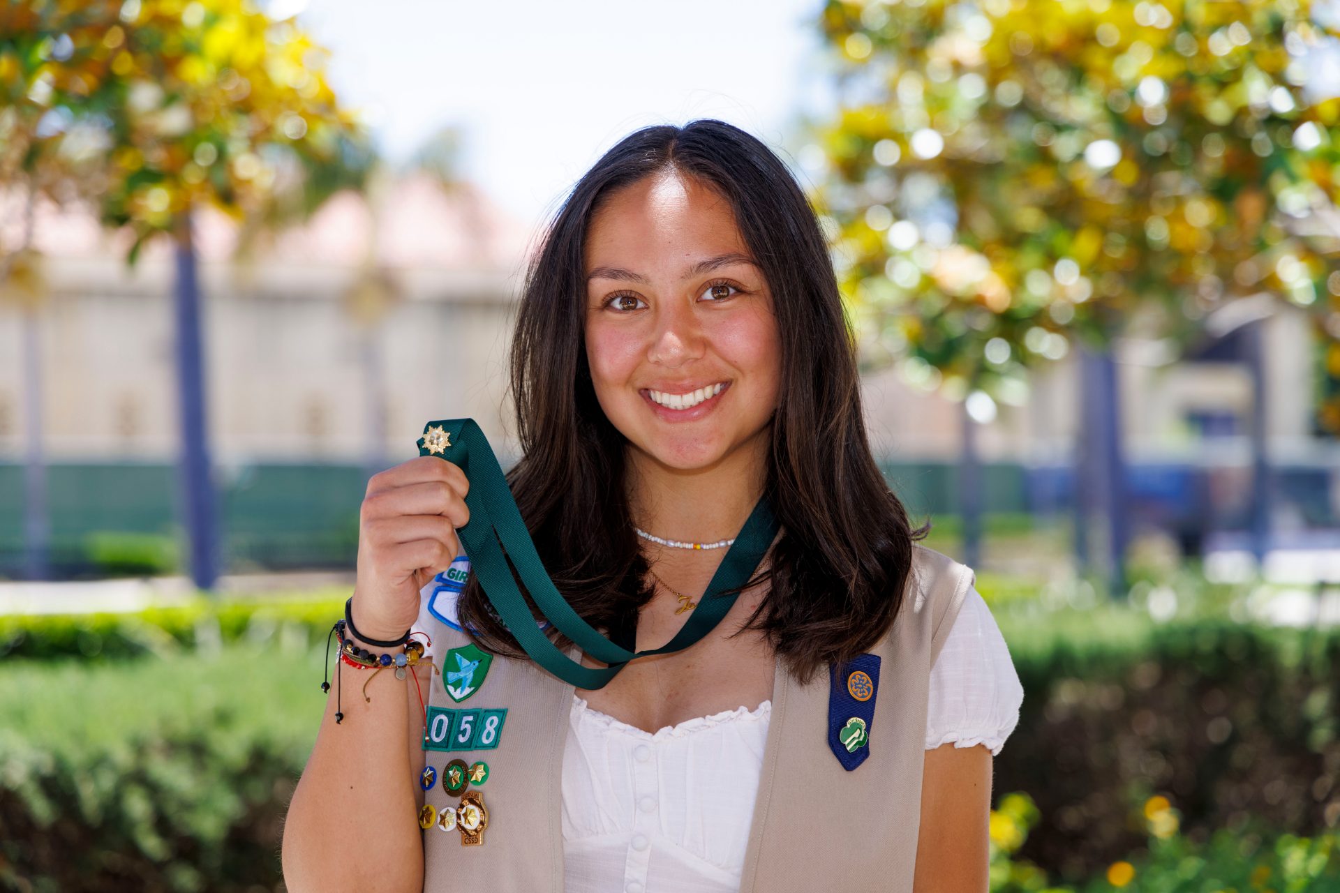 ambassador high school girl scout wearing sash outside against green background