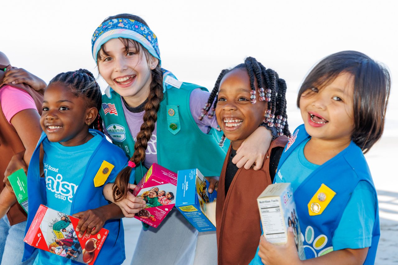 Troop leader with two Girl Scouts smiling outdoors