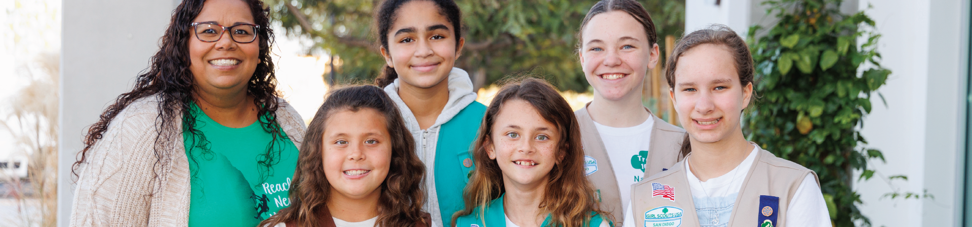  portrait of ambassador girl scout wearing vest and smiling at camera in front of a brick building 